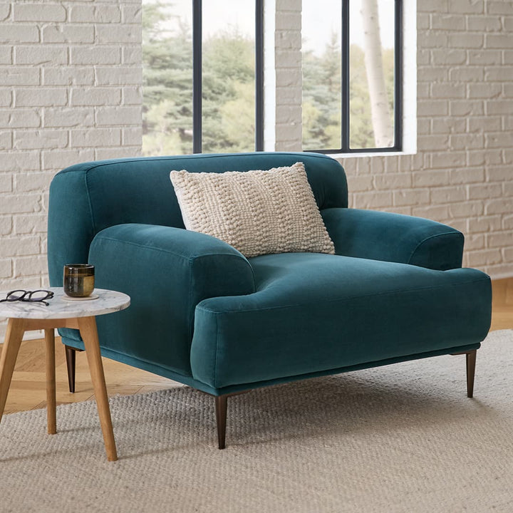 Lumina Velvet Lounge Chair in emerald velvet with titanium legs, showcasing draped-leg lounging posture
