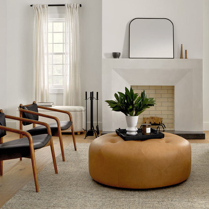 Mohn Leather Ottoman in a modern living room as a tufted leather footrest and coffee table