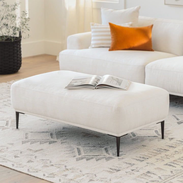 Nordkapp Ottoman with linen-blend upholstery and brushed aluminum legs in a modern living room