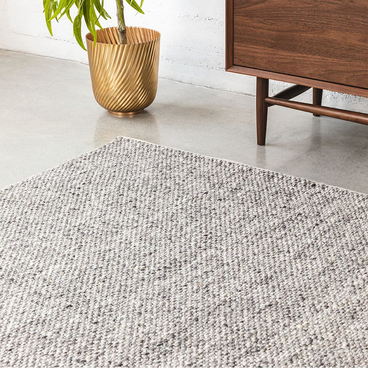 Silvanus Hand-Woven Wool Rug in a bohemian living room with wood floors and neutral decor